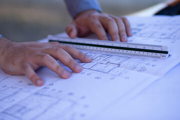 A pair of hands working on an architectural plan with a scaler

