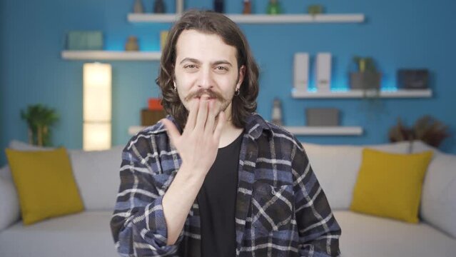 The man is making a heart against the camera. He's sending a kiss.
Man looking at camera makes a heart sign with his hand and kisses the camera. The state of love.
