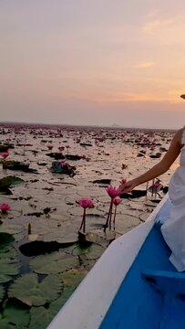 Asian women in a wooden boat during sunrise at the red lotus lake in Thailand , Sunrise at The sea of red lotus, Lake Nong Harn, Udon Thani, Thailand
