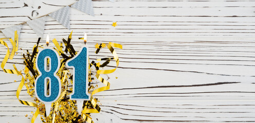 Number 81 blue celebration candle on white wooden background. Happy birthday candles. Concept of celebrating birthday, anniversary, important date, holiday.