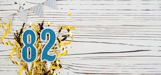 Number 82 blue celebration candle on white wooden background. Happy birthday candles. Concept of...