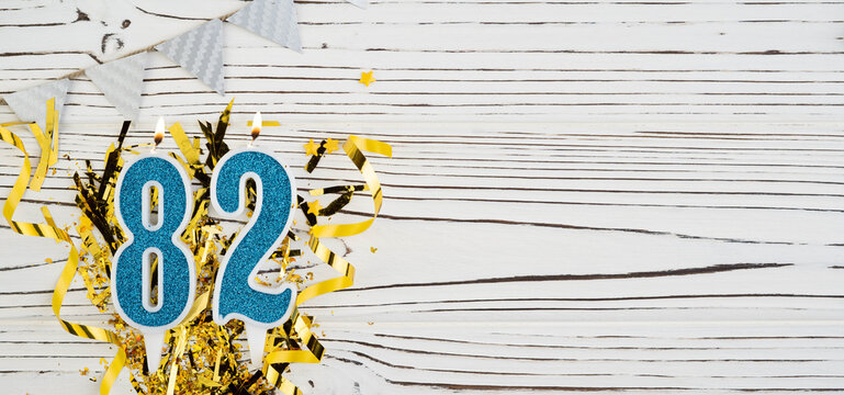 Number 82 blue celebration candle on white wooden background. Happy birthday candles. Concept of celebrating birthday, anniversary, important date, holiday. Copy space.