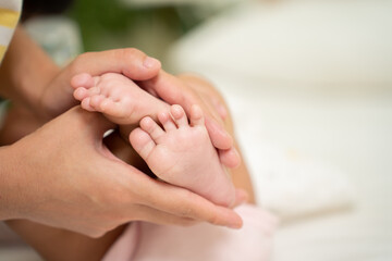 Obraz na płótnie Canvas Asian Baby feet in mother's hands that mean symblo of love. Mom and her Baby Child. Happy Family concept. Beautiful conceptual image of Mother and newborn baby family