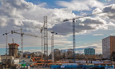 Fototapeta na wymiar Large construction site in Richmond City with construction cranes working on a construction complex where foundations are laid and construction of floors of high-rise buildings has begun