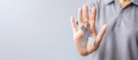 Brain Cancer Awareness month, woman hand holding grey color Ribbon for supporting people life. Healthcare and World cancer day concept