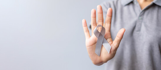 Brain Cancer Awareness month, woman hand holding grey color Ribbon for supporting people life....