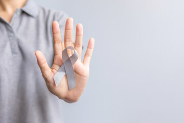 Brain Cancer Awareness month, woman hand holding grey color Ribbon for supporting people life. Healthcare and World cancer day concept
