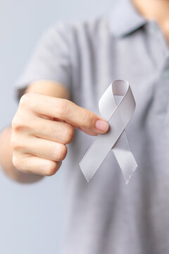 Brain Cancer Awareness month, woman hand holding grey color Ribbon for supporting people life. Healthcare and World cancer day concept