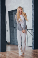 Obraz premium Vertical shoot of blonde Swedish girl in casual laughing comes in new apartment with fluttering hair, happy purchased home. Adorable shy caucasian young woman enjoying weekend. Smile. Romance, love.