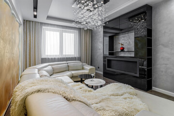 Living room with white walls and a huge white sofa, a black glossy wardrobe with a large yellow 3D panel on the wall as well as bio fireplaces