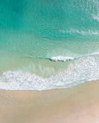 Fototapeta na wymiar Aerial view of a beach with stunning clear water and warm white sand in a holiday paradise near the Pacific Ocean