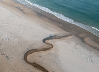 Fototapeta na wymiar Aerial photography of a creek path pouring out onto the ocean