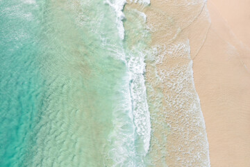 Fototapeta na wymiar Aerial view of a beach with gentle waves and white sand in a tropical wonderland