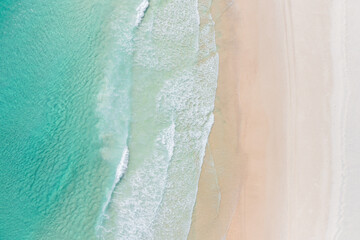 Aerial view of a beach with gentle waves and white sand in a tropical wonderland