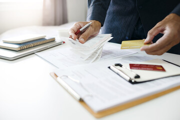 Asian businessman hand holding credit card checking invoice and bank statement trying to find money to pay credit card debt and all loan bills. Financial problem from inflation economy concept