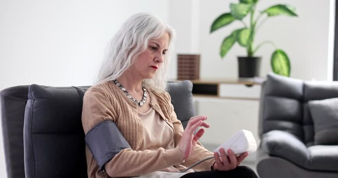 Elderly woman measuring blood pressure with electronic sphygmomanometer at home 4k movie slow motion