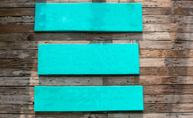 Three blue wooden signs on a wooden wall