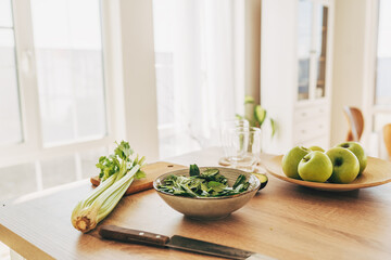 Blended green smoothie with ingredients on wooden table