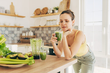 Matcha green vegan smoothie with chia seeds and mint in glass in hands of female wearing white sweater, square crop. Clean eating, alkaline diet, weight loss food concept.