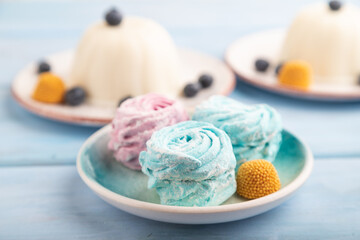 White milk jelly with marshmallow on blue wooden, side view, selective focus.