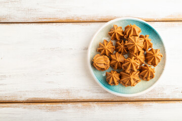 Homemade soft caramel fudge candies on white wooden, top view, copy space.