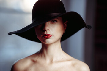 Close-up beautiful female face in a hat. Beautiful girl in black hat on her head. Isolated on dark blurred background. Pretty Woman portrait