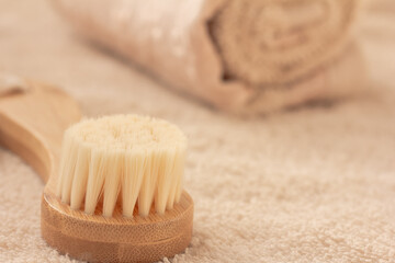 Soft Beige towel and wooden brush on beige background. Bathroom accessories. Skin care, wellness concept, copy space