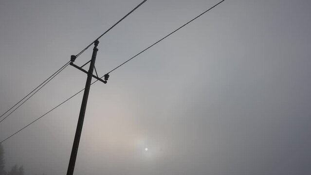 power pole in the morning fog at sunrise