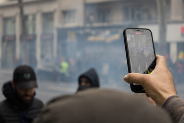 main tenant un portable qui filme une révolte dans la rue