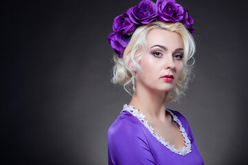 Beauty Concept. Winsome Caucasian Female Posing in Purple Dress with Flowery Violet Crown.