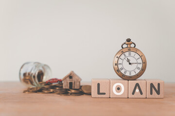 For refinance, banking, house loan, reverse mortgage .Vintage clock on wooden cube block with LOAN text  , blurred  miniature house, small car and coins