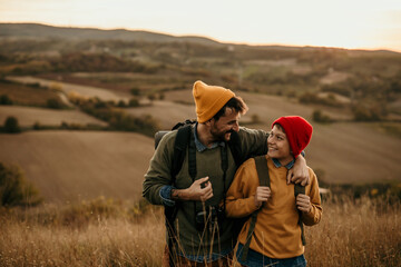 Image of a young father walking and talking with his teenage son in an autumn field, exploring and having fun.