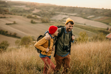 Father and son embraced talking and walking in a grass field during the nature sunset.
