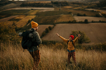 Father with son trekking in mountains during a weekend vacation. Son runs toward his dad for a hug...