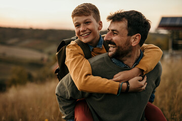 Photo of father and his son enjoying a beautiful autumn day on a natural hill. Close up