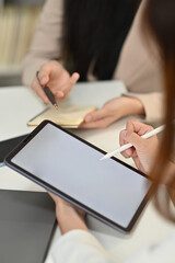 Close up view of female employee sitting at meeting table and using digital tablet