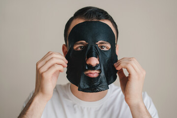 Portrait of handsome man enjoying spa and self care day having skincare facial mask on his face at home - cosmetology concept