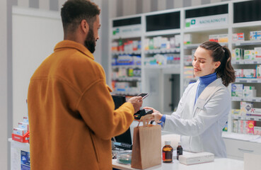 Young multiracial man paying for medication in pharmacy.