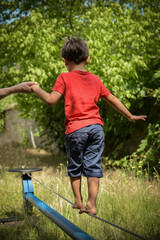 young boy walking on a wire with the help of a woman coach