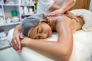 client receives physical therapy from a massage therapist on her shoulders and back in spa.