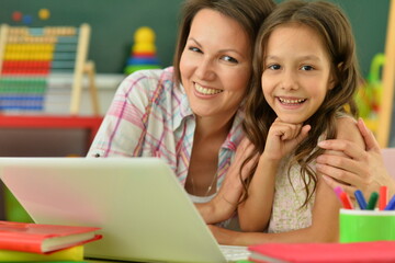 portrait of mother and daughter using laptop