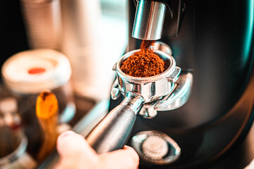 Hands preparing grounded coffee beans in espresso machine for a cappuccino