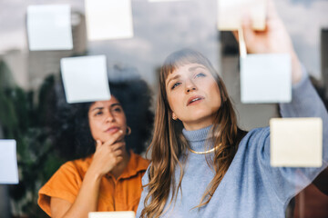 Two young businesswomen brainstorming using sticky notes