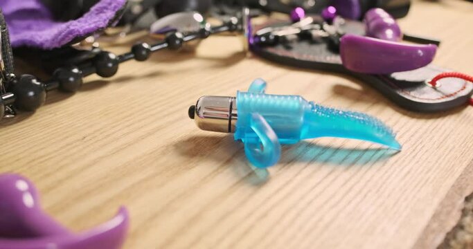 Vibrator is spinning in a circle among a variety of sex toys, fetishism. Side view, close-up.