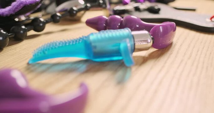 Variety of sex toys are scattered on table. Flight of the camera over the table, close-up. Fetish set, vibrator for pleasure.