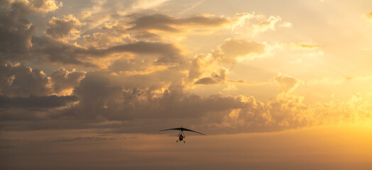 Propeller plane flies in the sunset sky. Banner, A small private hang-glider in a cloudy sky.