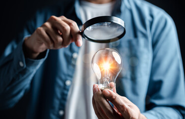 Businessman focus with magnifying to light bulb with business target planning idea and creativity...