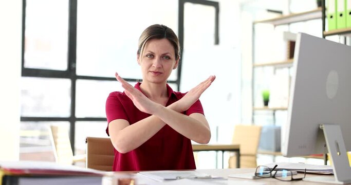 Woman with serious face shows crossed arms and symbol of refusal and stop