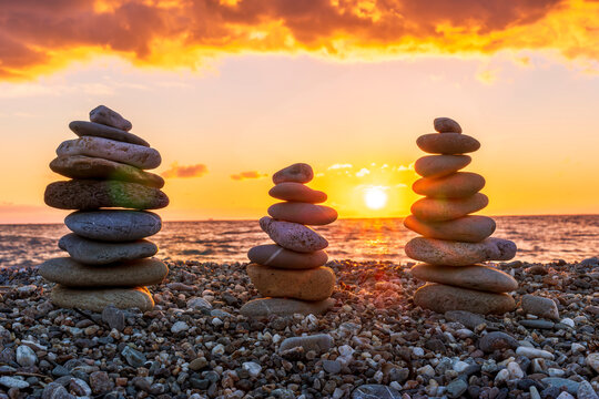 three towewrs or turrets of stone in a nice empty sea beach with coast line guring sunset or sunrise with amazing cloude sky on baclground - Powered by Adobe