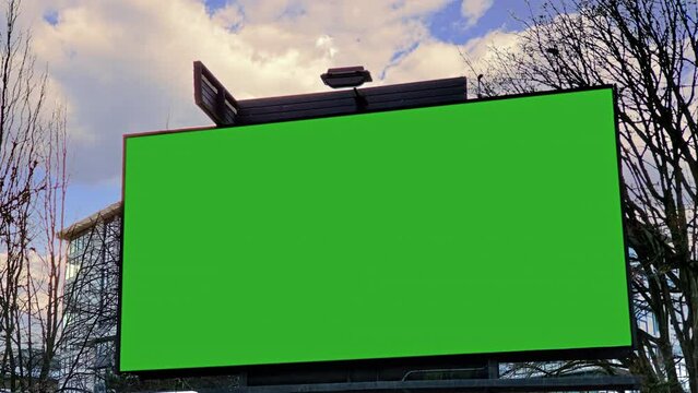 Green Screen Billboard Panel Street Cloudy Sky Background. Low angle shot of an outdoor billboard green screen on a cloudy day. Steady shot